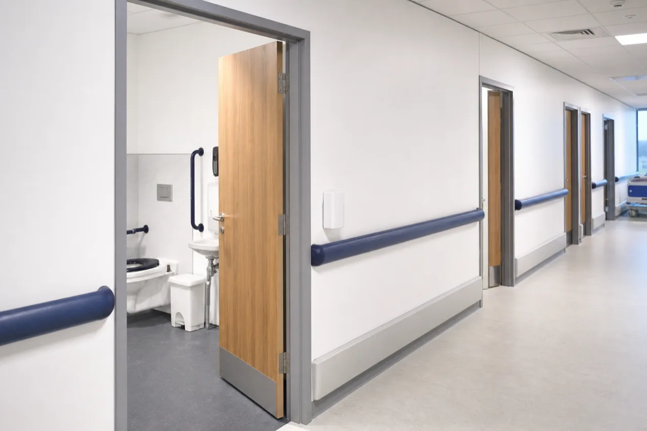 Corridor d'hôpital avec porte de salle de bains patient, éclairage clinique